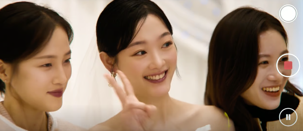 Lee Yoo-mi smiling in a wedding dress alongside her friends in a camera screen view from As You Stood By